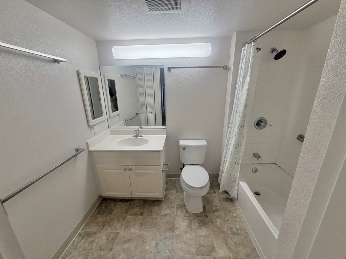 A white bathroom with a toilet, sink, and shower.